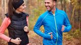 Twee mensen joggen samen over een bospad.